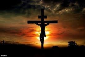 This is an image of Jesus on the cross with the sun setting behind him.